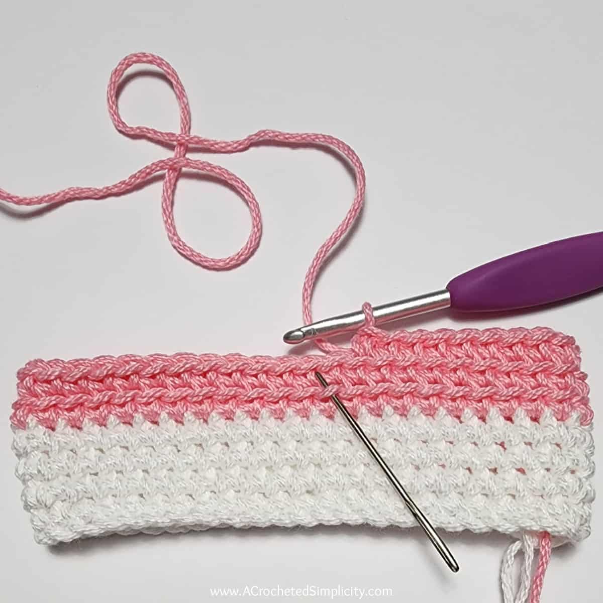 Crochet Valentine's Day treat bag tutorial photo in pink and white yarn showing where to work the next stitch.