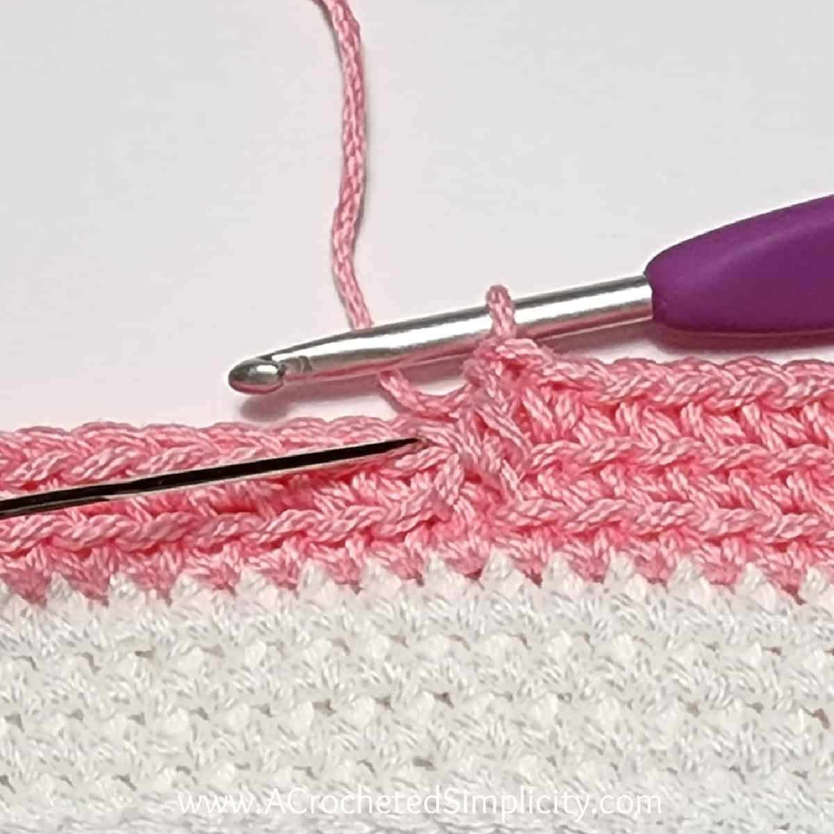 Crochet Valentine's Day treat bag tutorial photo in pink and white yarn showing where to work the next stitch in back loop only.