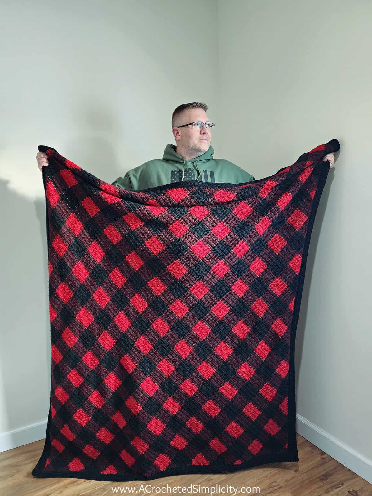 This image shows my husband holding up his new Buffalo Plaid Crochet Blanket.