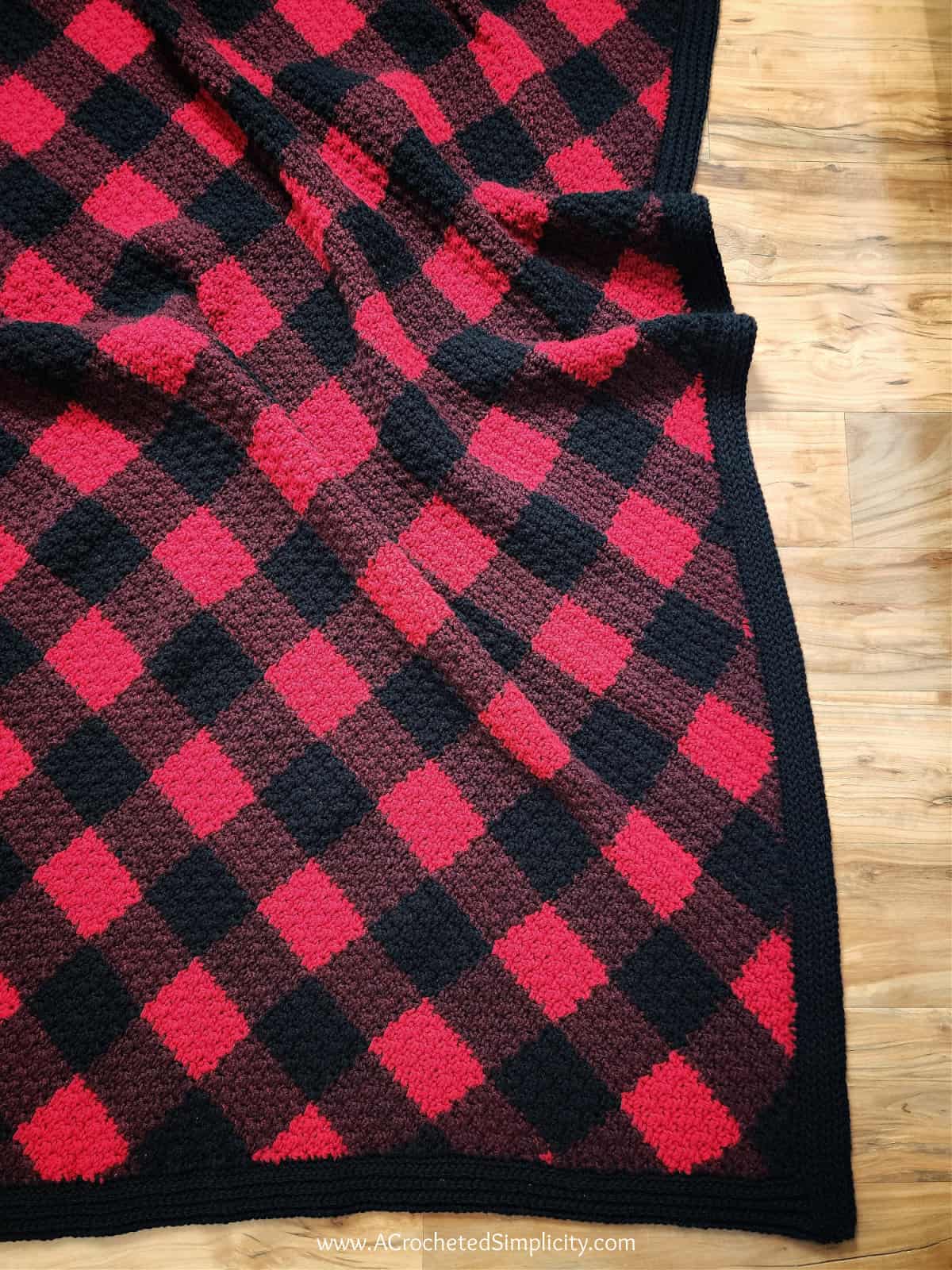 C2C crochet plaid blanket laying on wood floor.