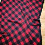 Corner to corner crochet buffalo plaid blanket laying on a wood floor.