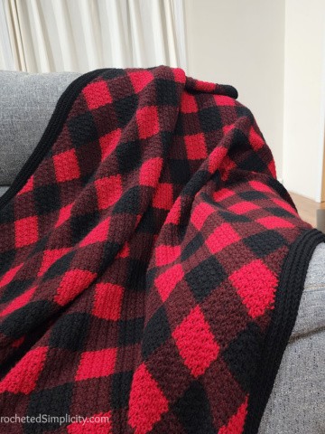 Close up of crocheted buffalo plaid blanket draped over the couch.