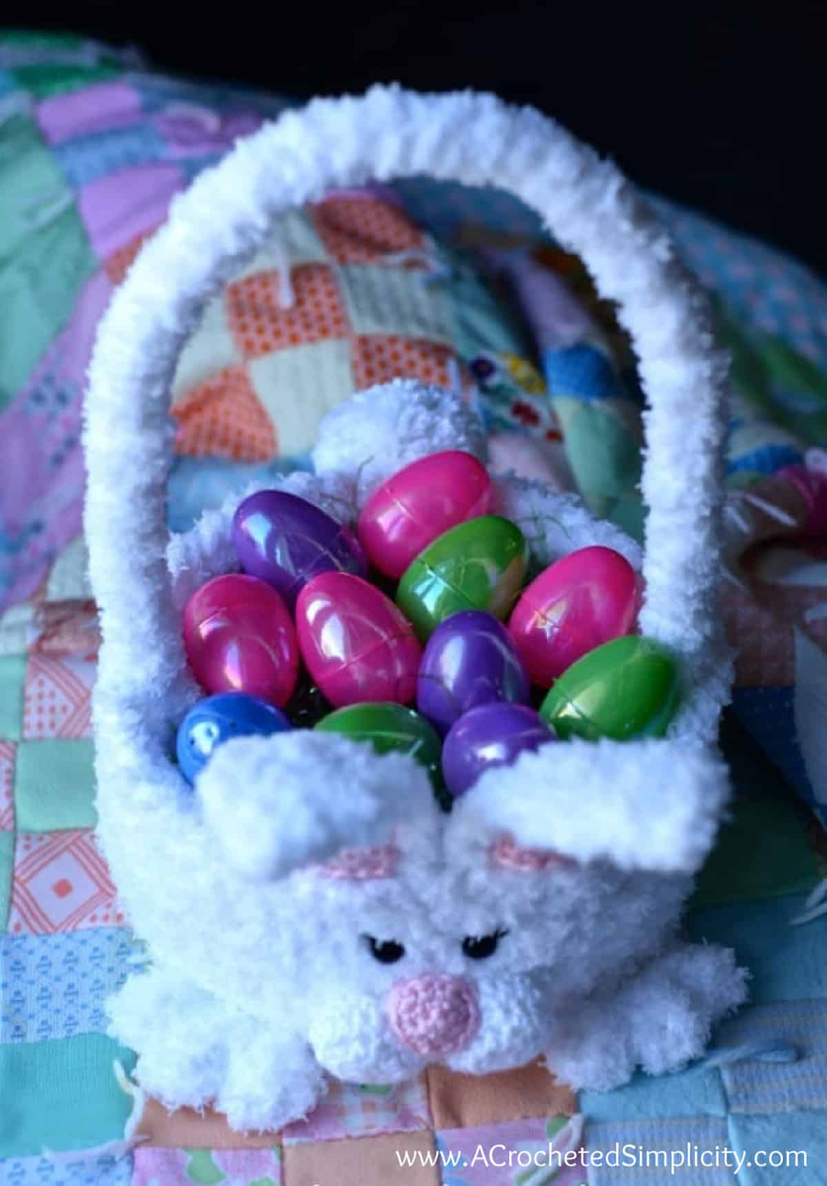 Top down image of crochet Easter bunny basket filled with plastic Easter eggs.