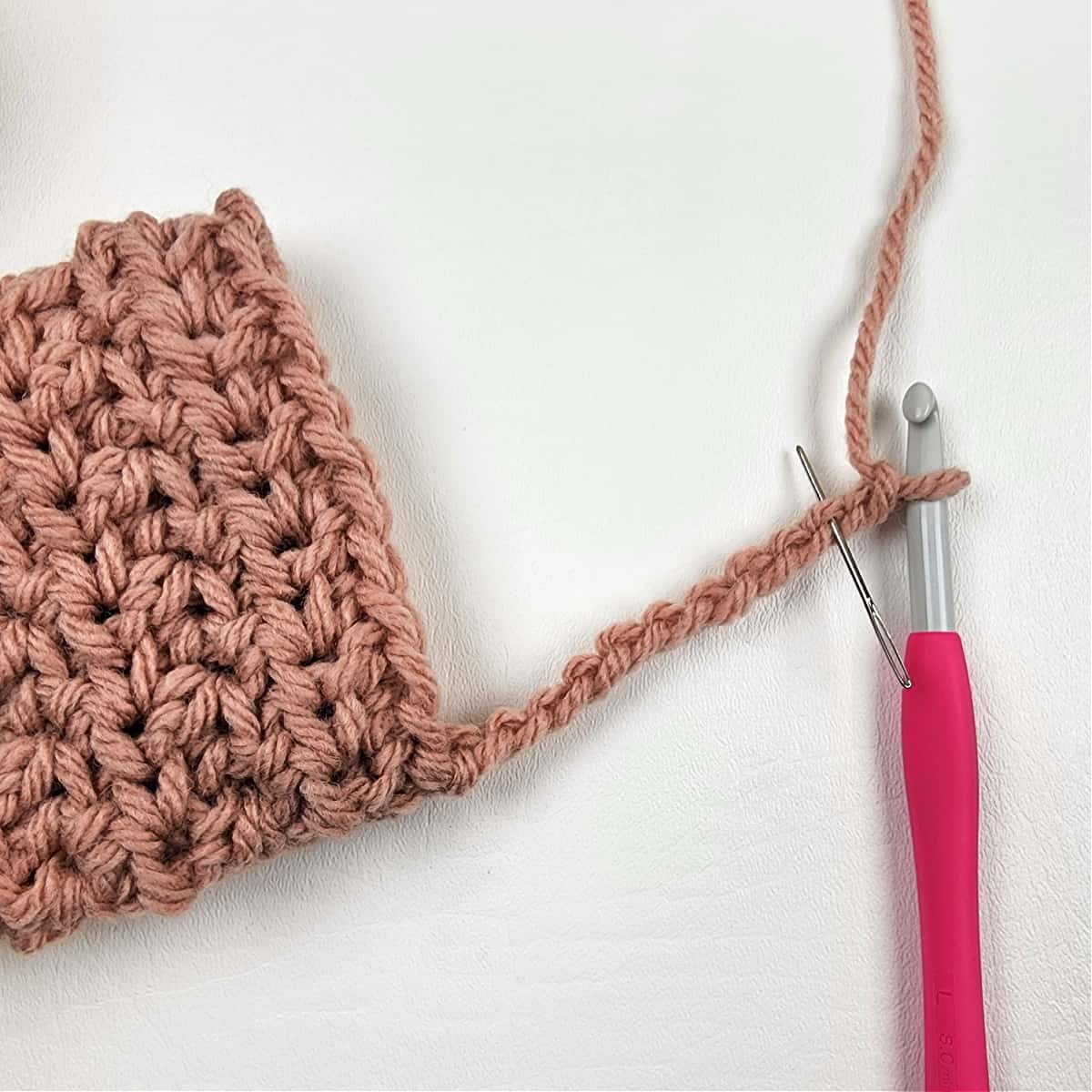 Step one photo of a crochet ribbed cuff with a pink crochet hook.