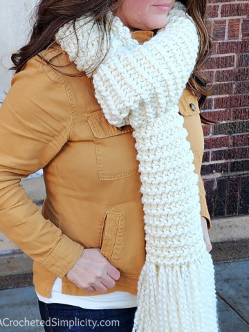 Close up of woman wearing a cream colored knit look crochet scarf.