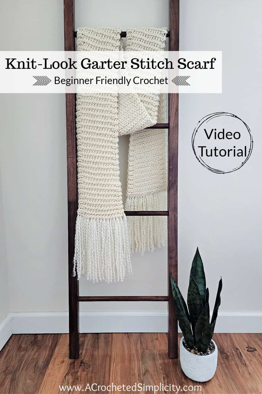 Knit look crochet scarf hanging on a wooden blanket ladder with potted plant.