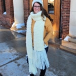 Woman modeling a knit look crochet hat and scarf in cream.