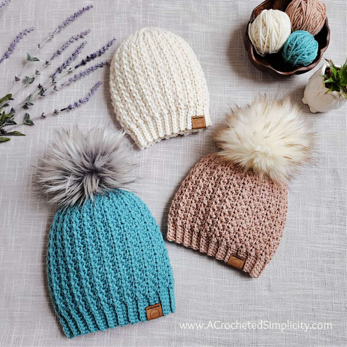 Three short row crochet hats laying with lavender and a yarn bowl.