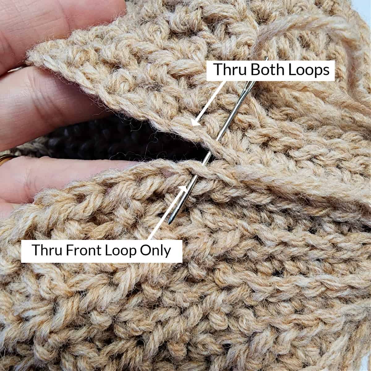 Yarn needle and white arrows showing direction to work the seam on the crochet hat.