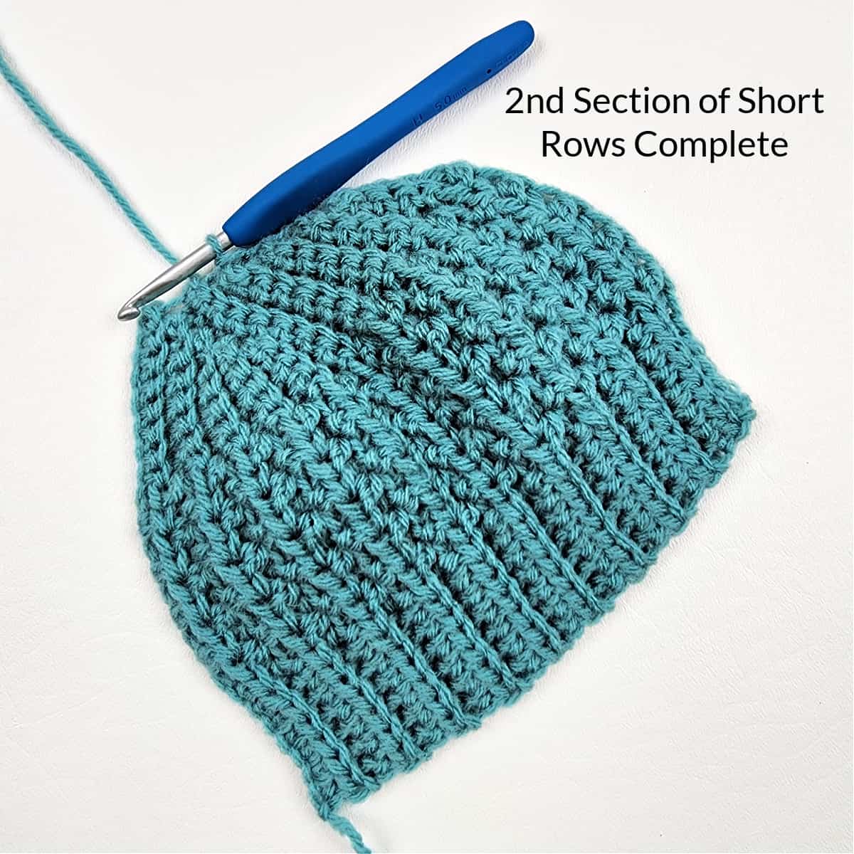 Two short row sections complete on a green crochet hat.