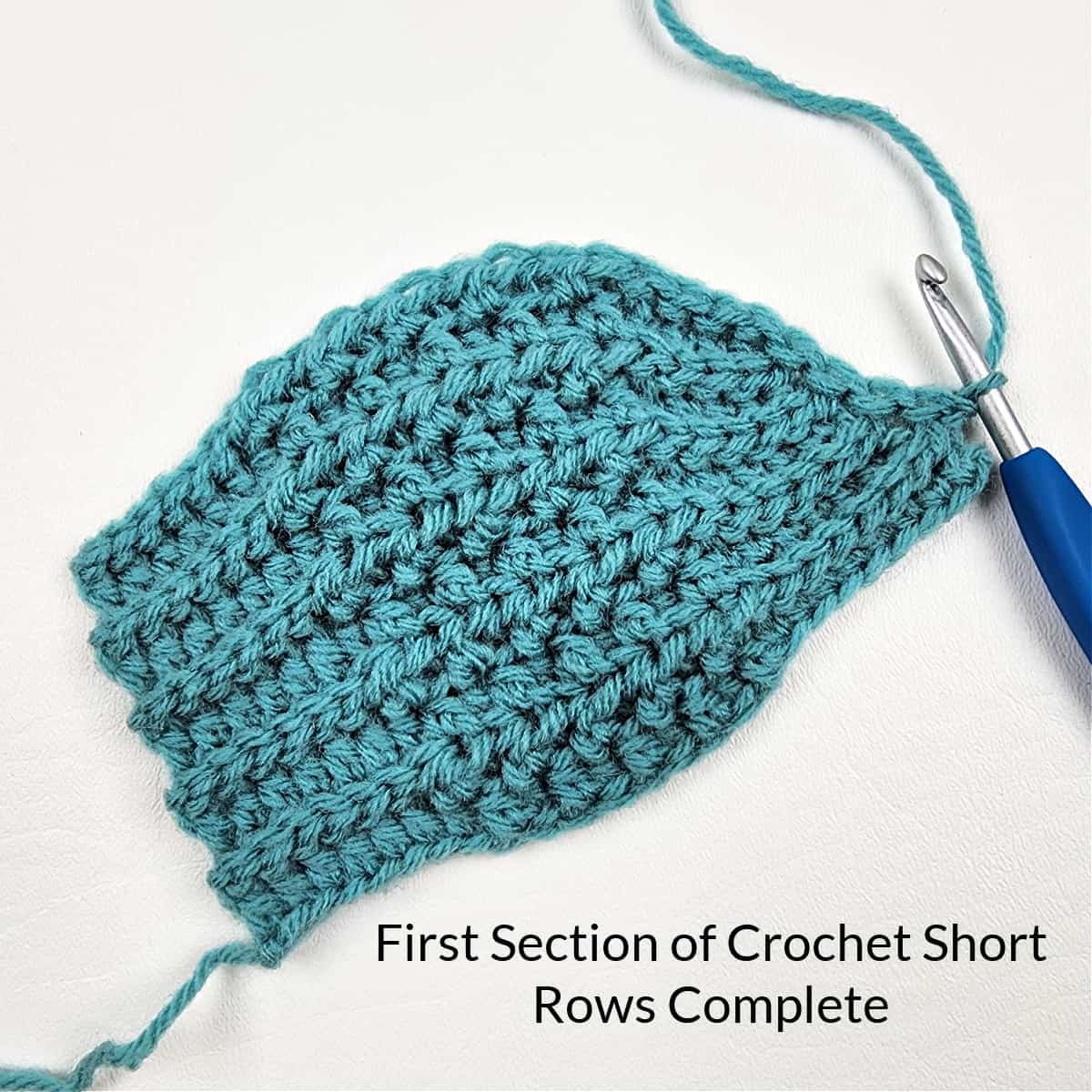 Front side of a crochet hat showing the first section of crochet short rows complete.