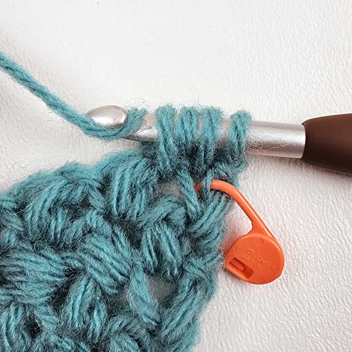 Small crochet swatch showing a mini bean stitch being made.