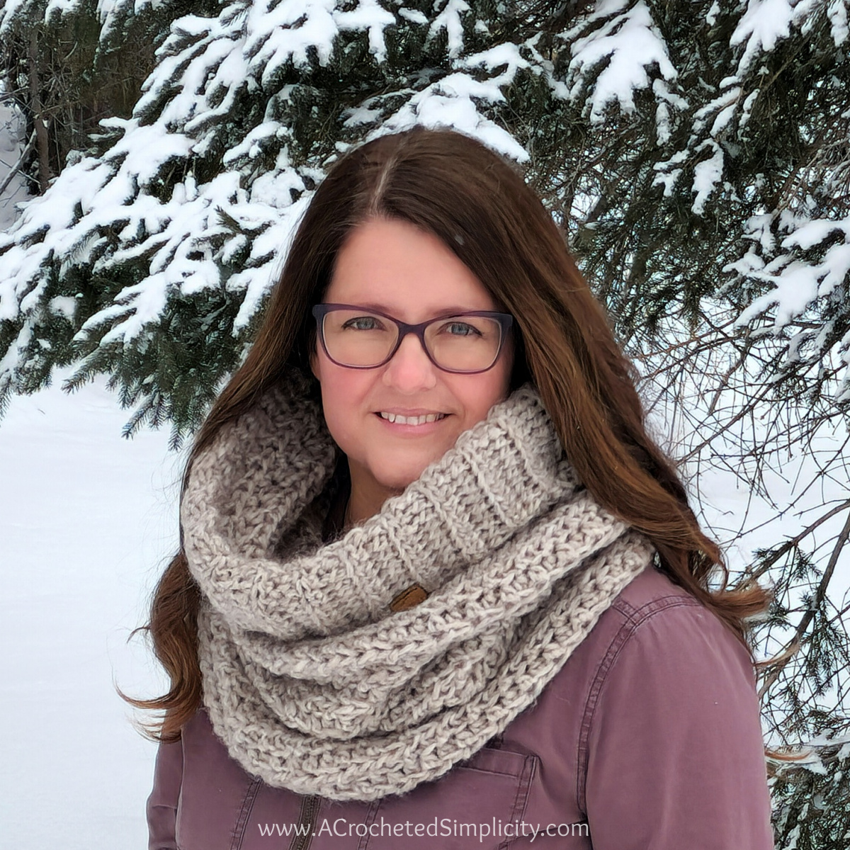 Crochet hooded cowl modeled by woman with long brown hair and glasses.