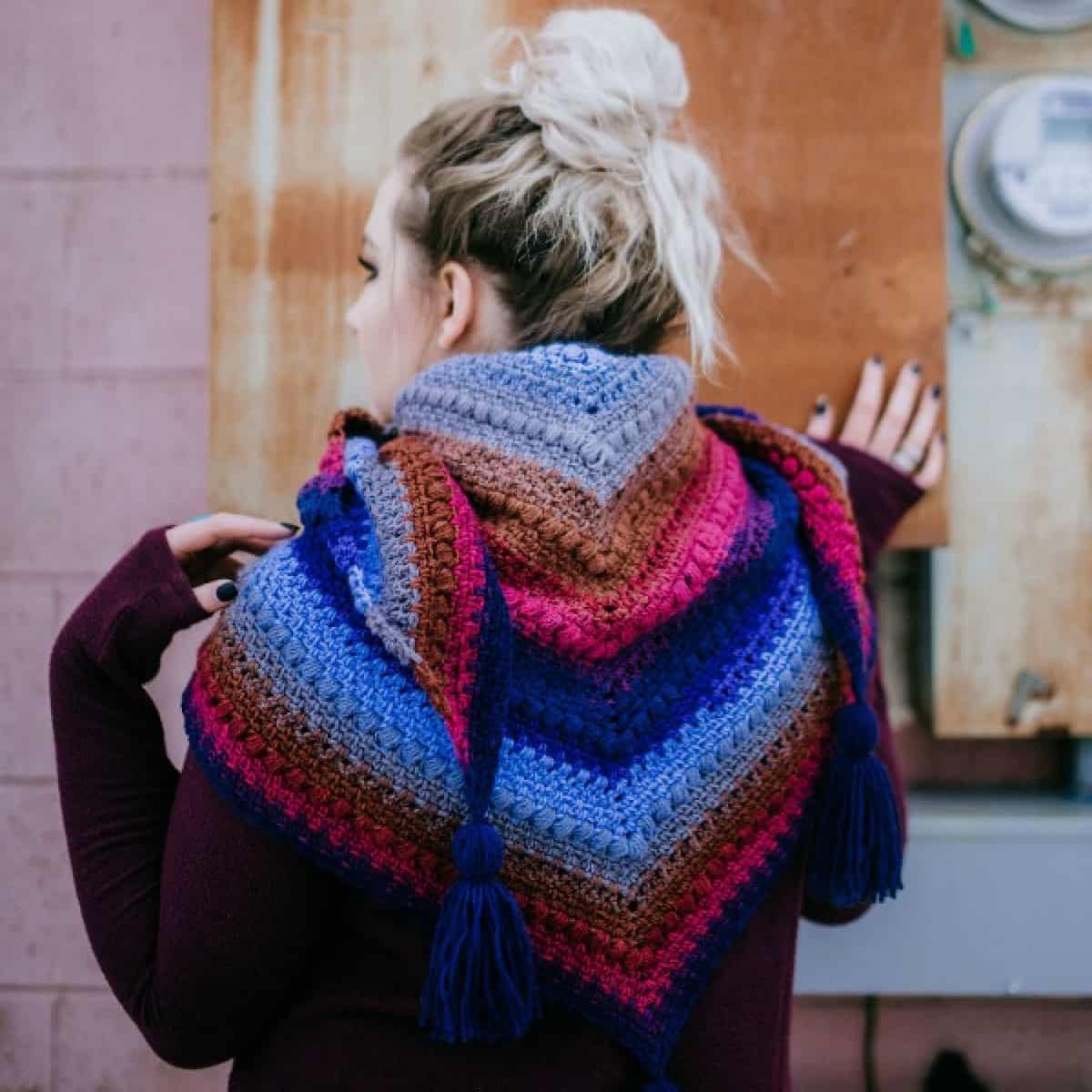 Woman modeling a triangular crochet shawl.
