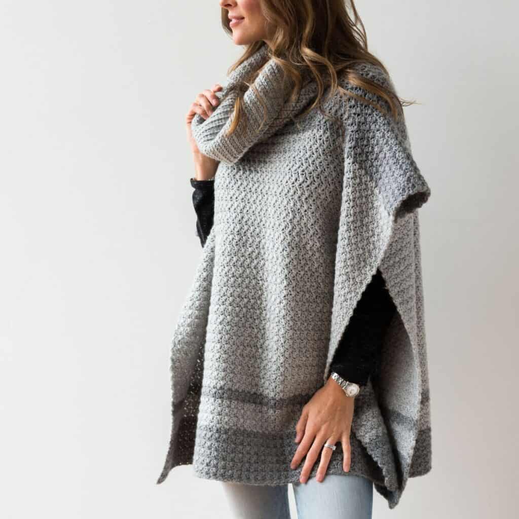 Modeled light and medium grey crochet poncho with a cowl neck.
