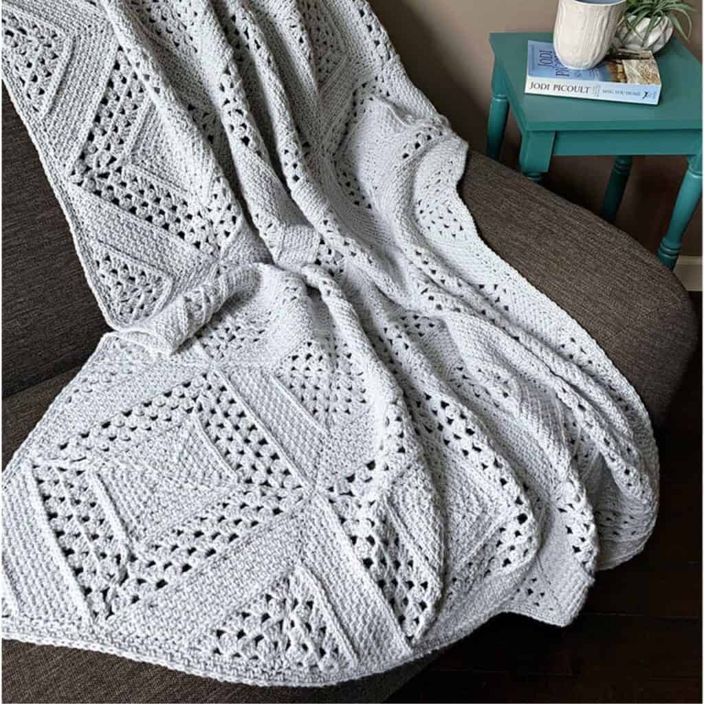 Light grey granny square blanket draped over a brown chair.