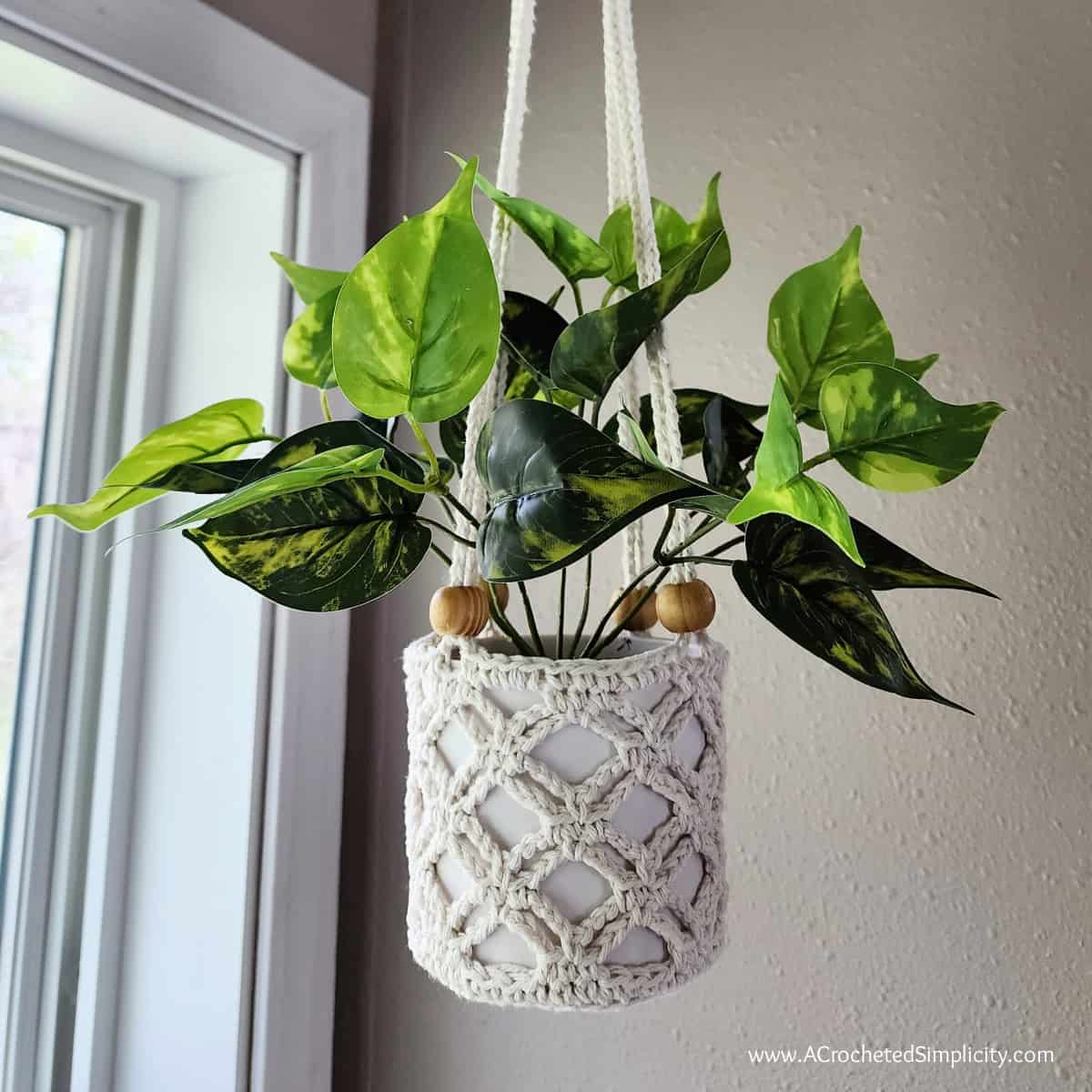 Close up of a medium size ecru crochet plant hanger with wooden beads.