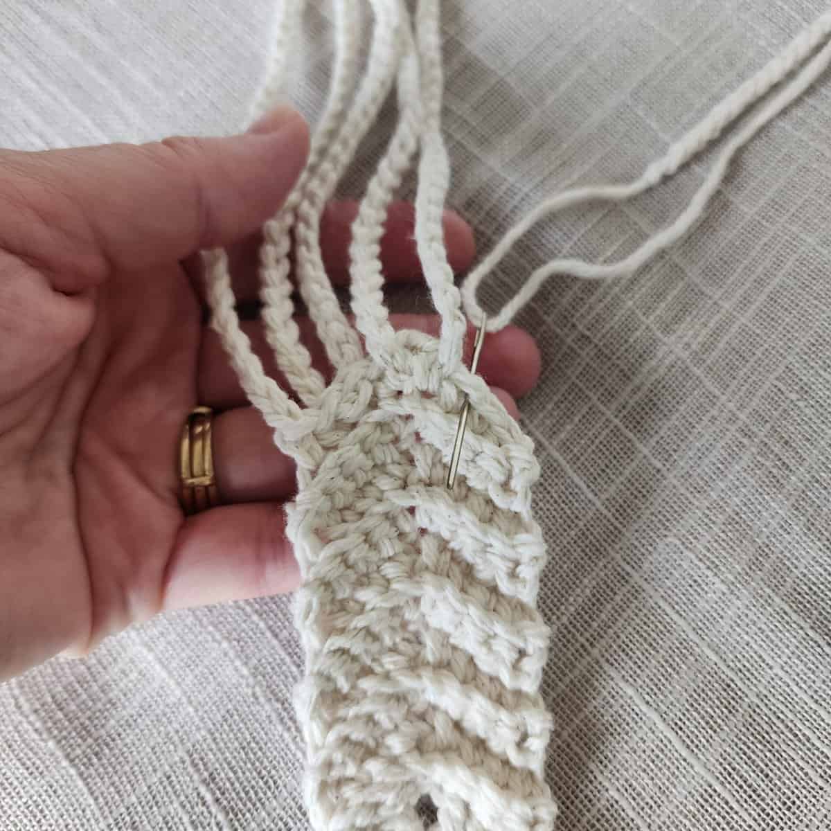 Third hanging strap being attached to hanging ring with yarn needle.
