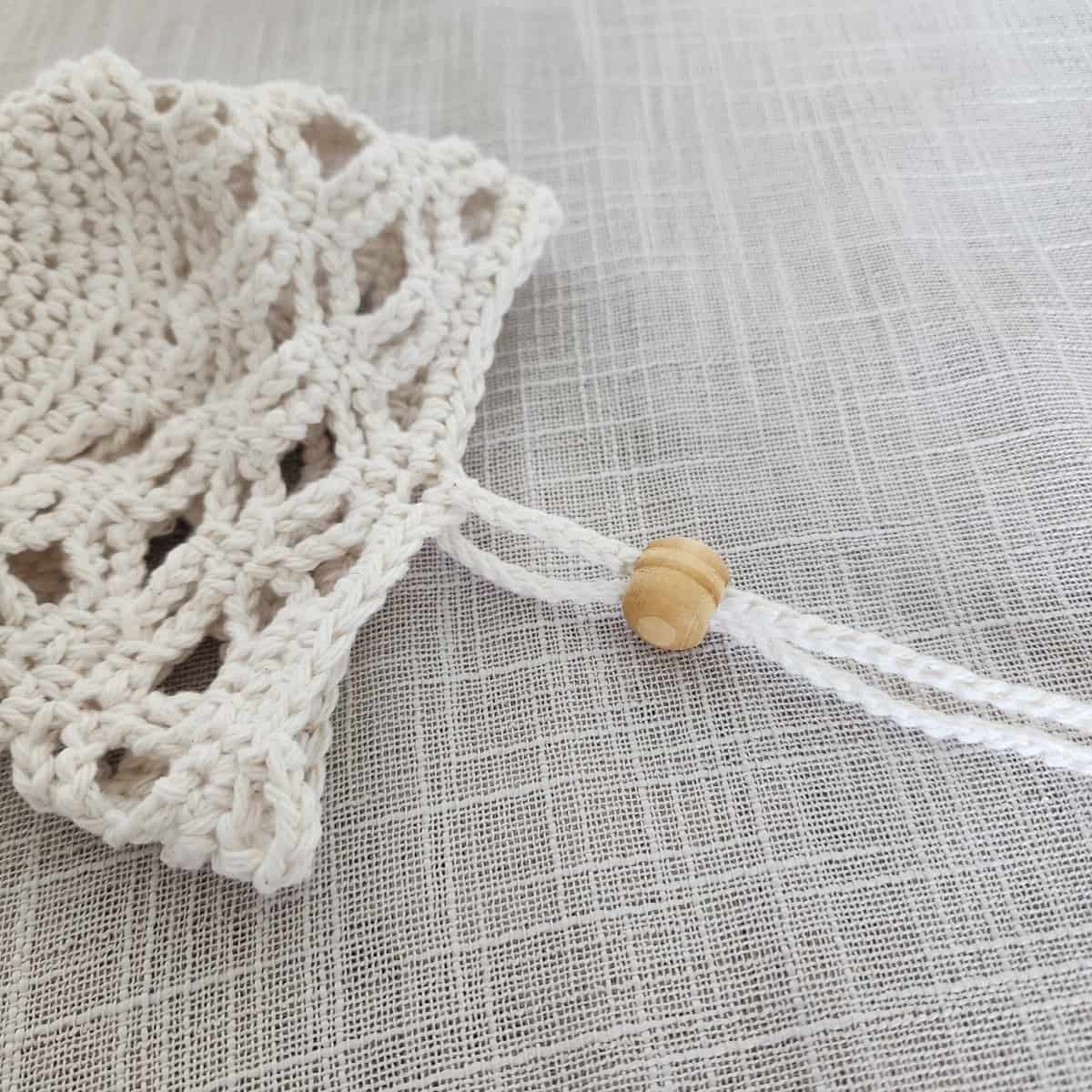 Close up of crochet plant hanger with wooden bead on the hanging strap.