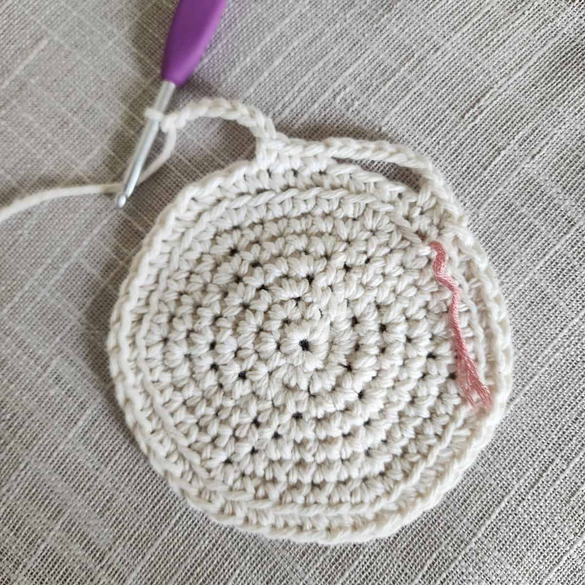 Small crochet circle with purple crochet hook.