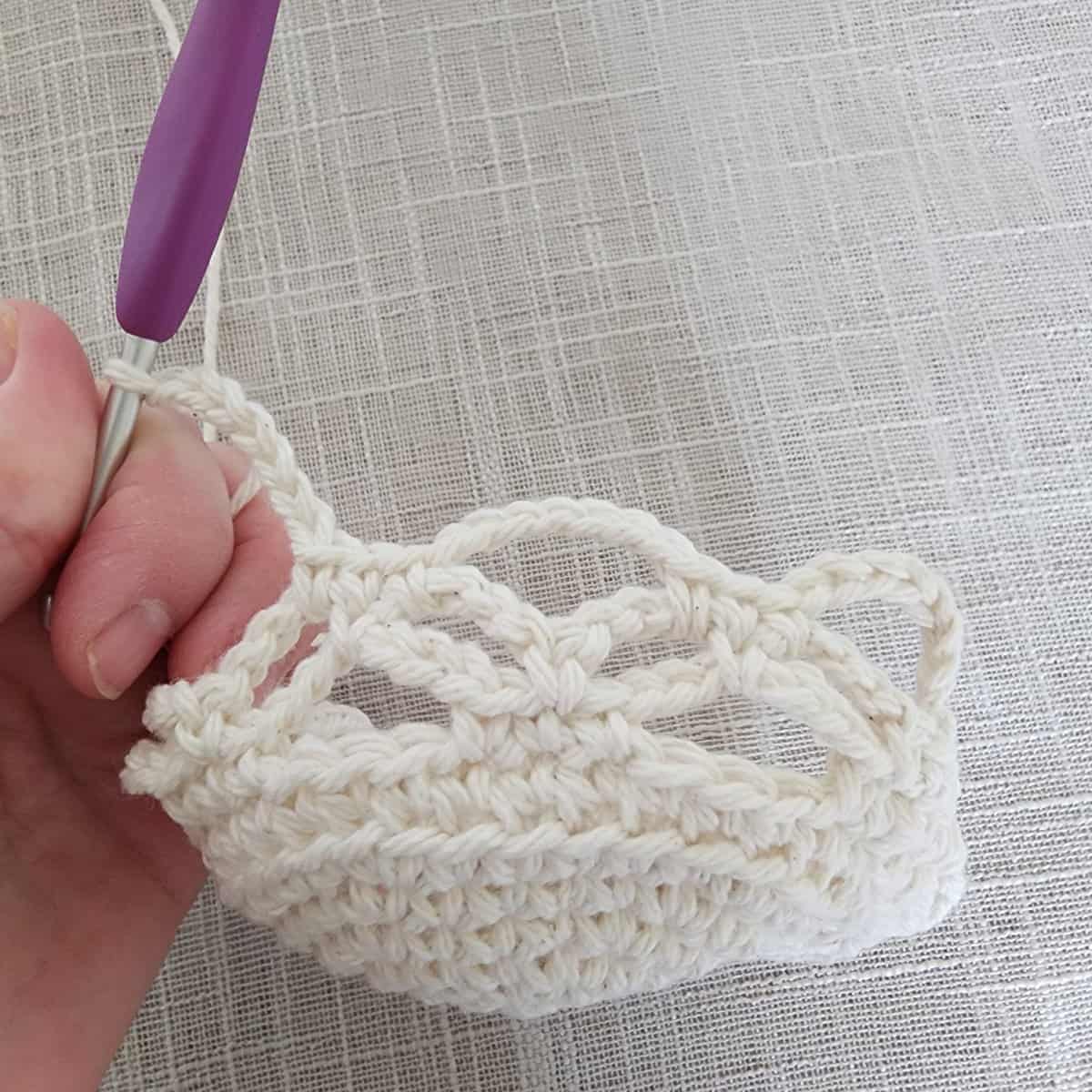 Progress of crochet lace stitch pattern and purple crochet hook.