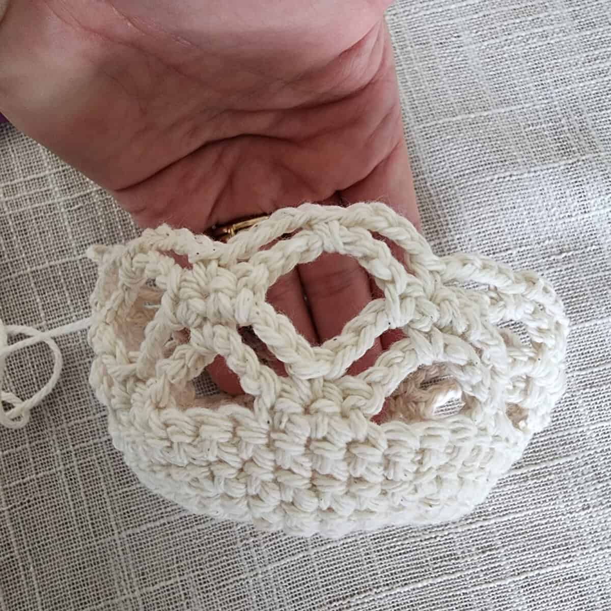 Hand holding crochet plant hanger basket.