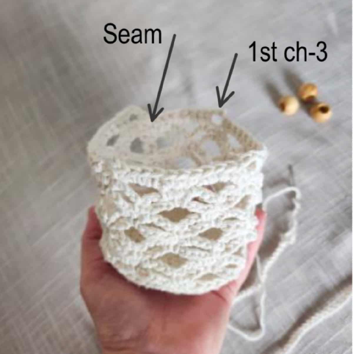 Hand holding crochet plant hanger basket.