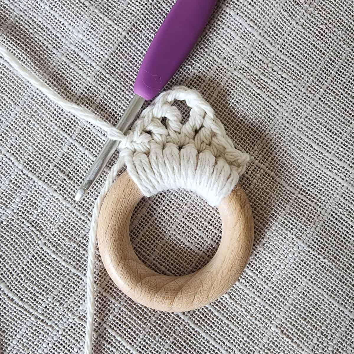Crochet around small wooden ring with ecru yarn.