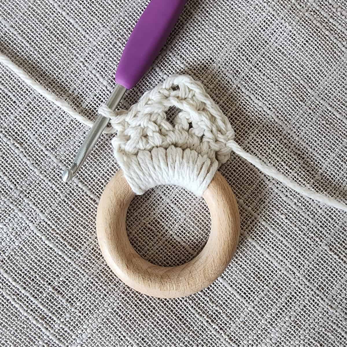 Small wooden ring with single crochet around and hanging strap being started.
