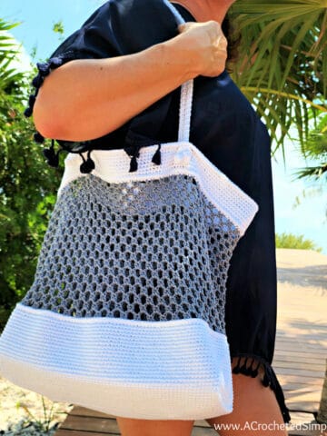 Woman carrying white and grey beach bag.
