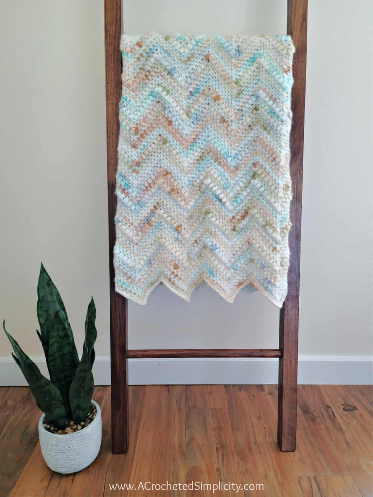 Crochet chevron blanket folded and hanging on blanket ladder.