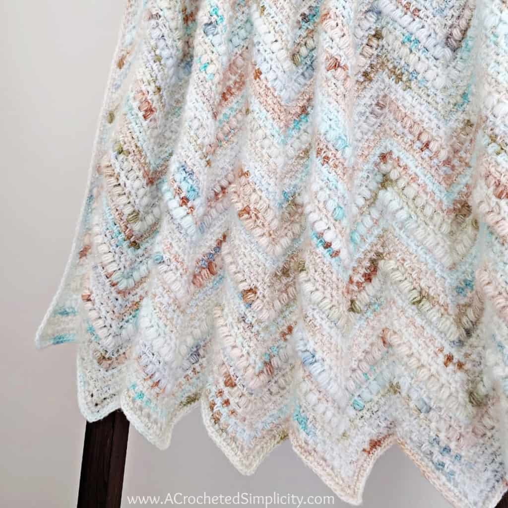 Close up of crochet chevron blanket folded and hanging on blanket ladder.