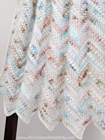 Close up of crochet chevron blanket folded and hanging on blanket ladder.