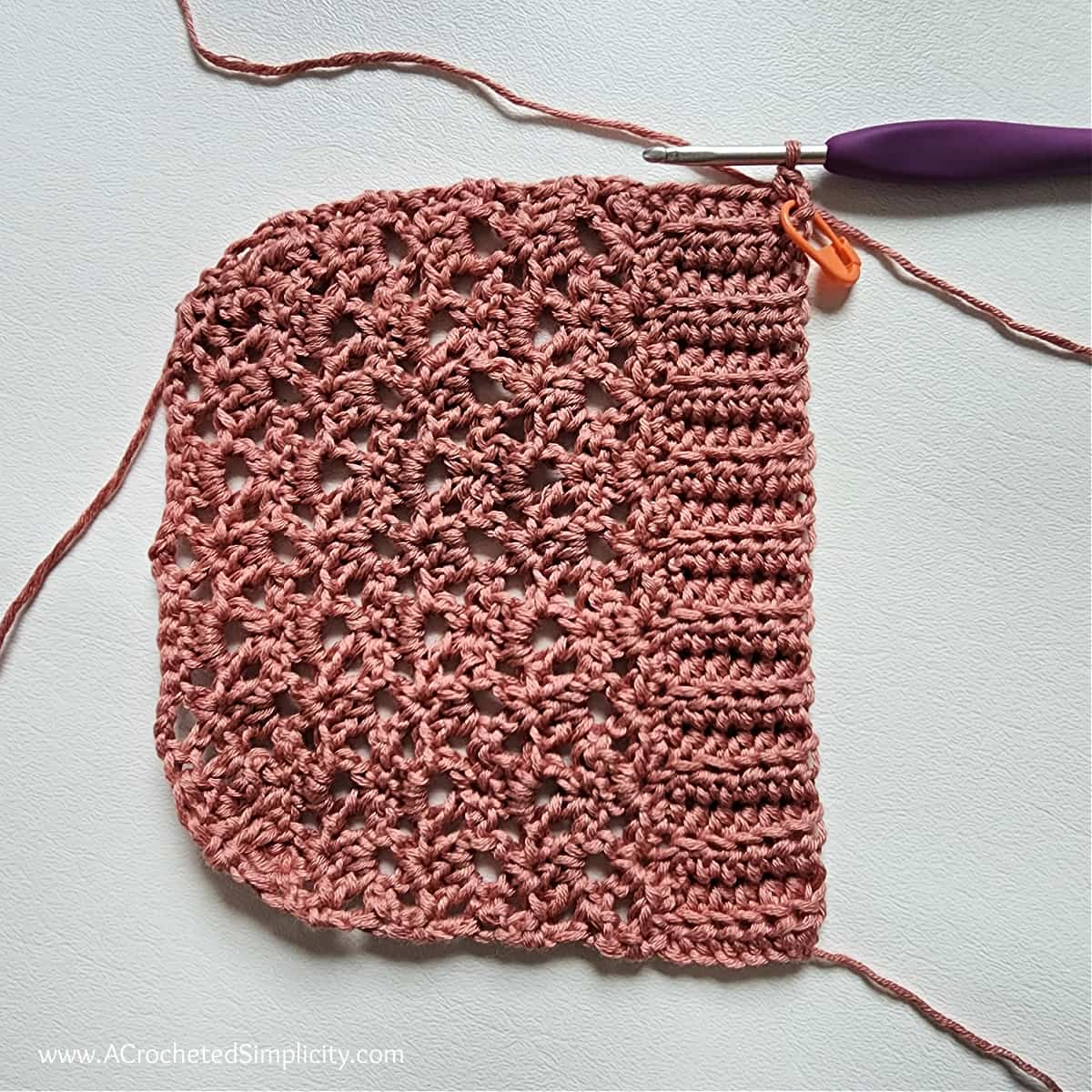 Crochet pocket laid sideways to begin edging with a purple crochet hook.
