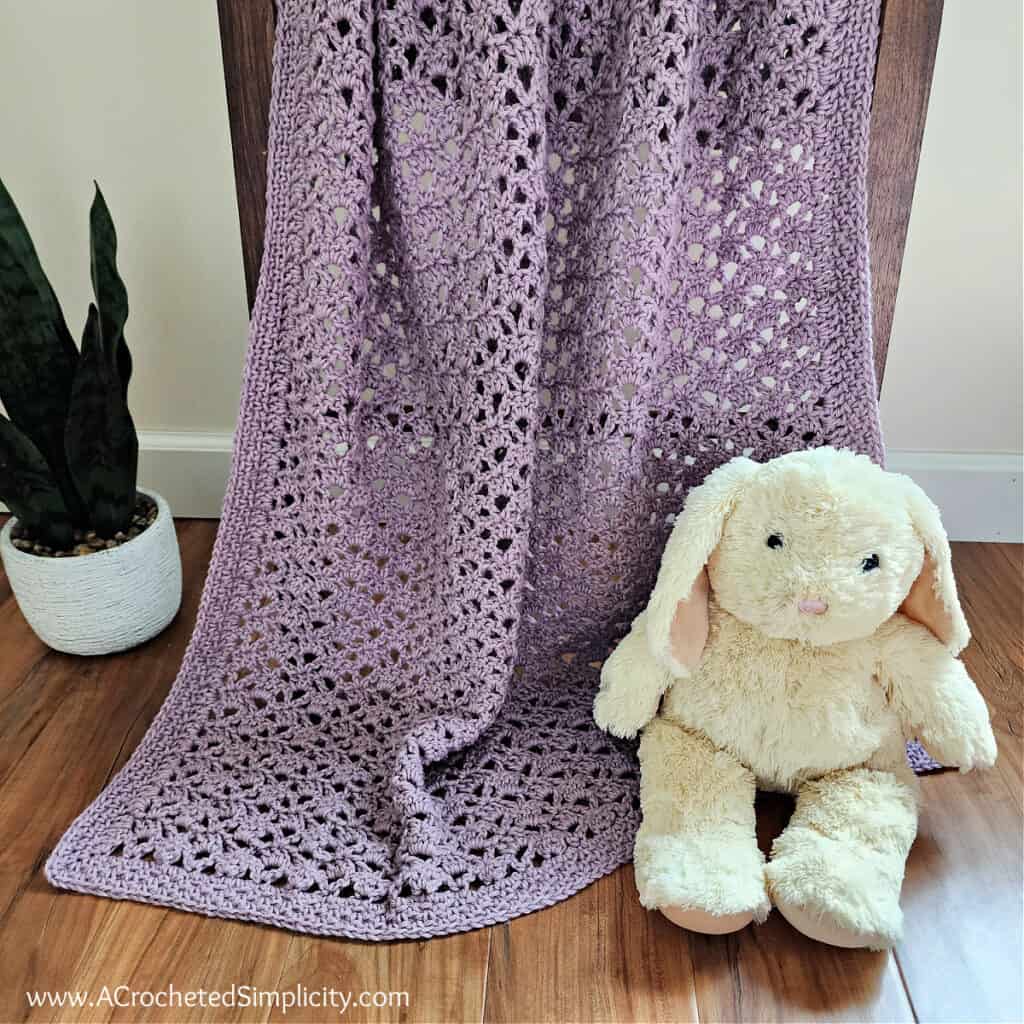 Lilac colored easy lacy baby blanket crochet pattern with a cream colored stuffed bunny
