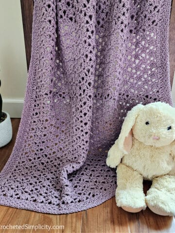 Lilac colored easy lacy baby blanket crochet pattern with a cream colored stuffed bunny