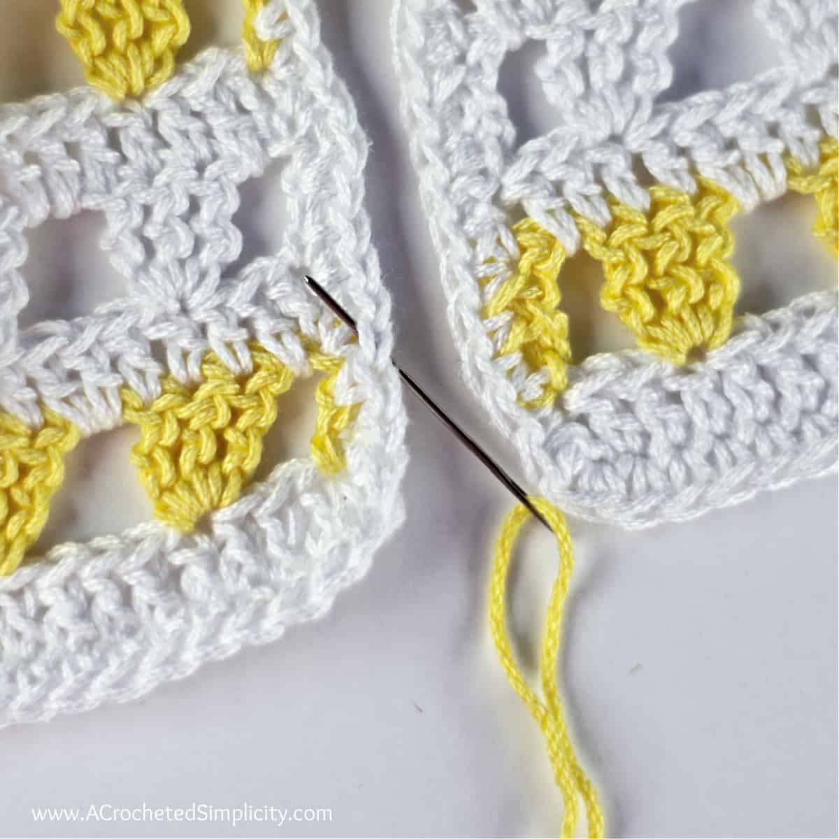 A needle with yellow yarn is being inserted into the crochet piece on the left, from bottom to top.