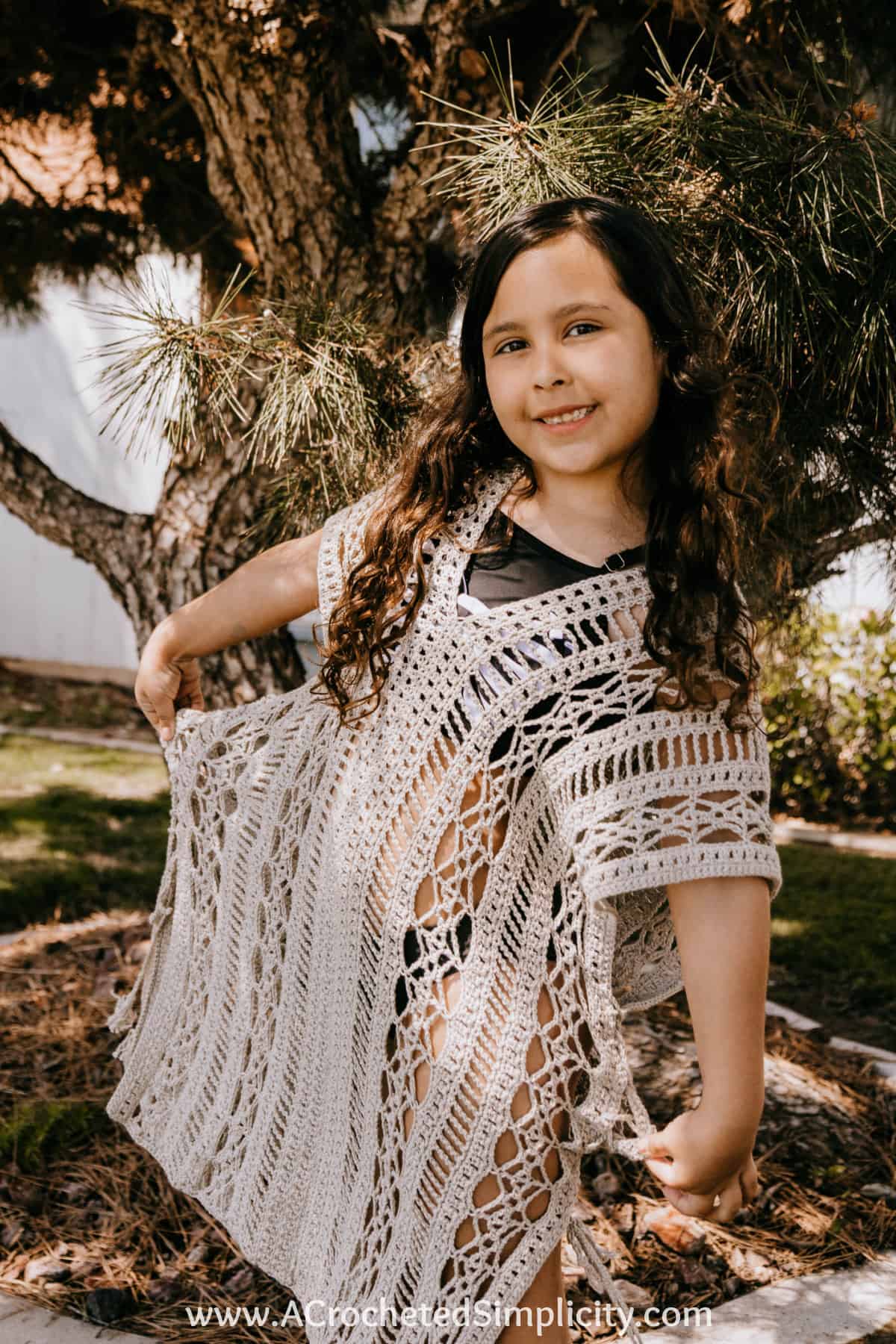 young girl modeling a crochet swim cover up in beige