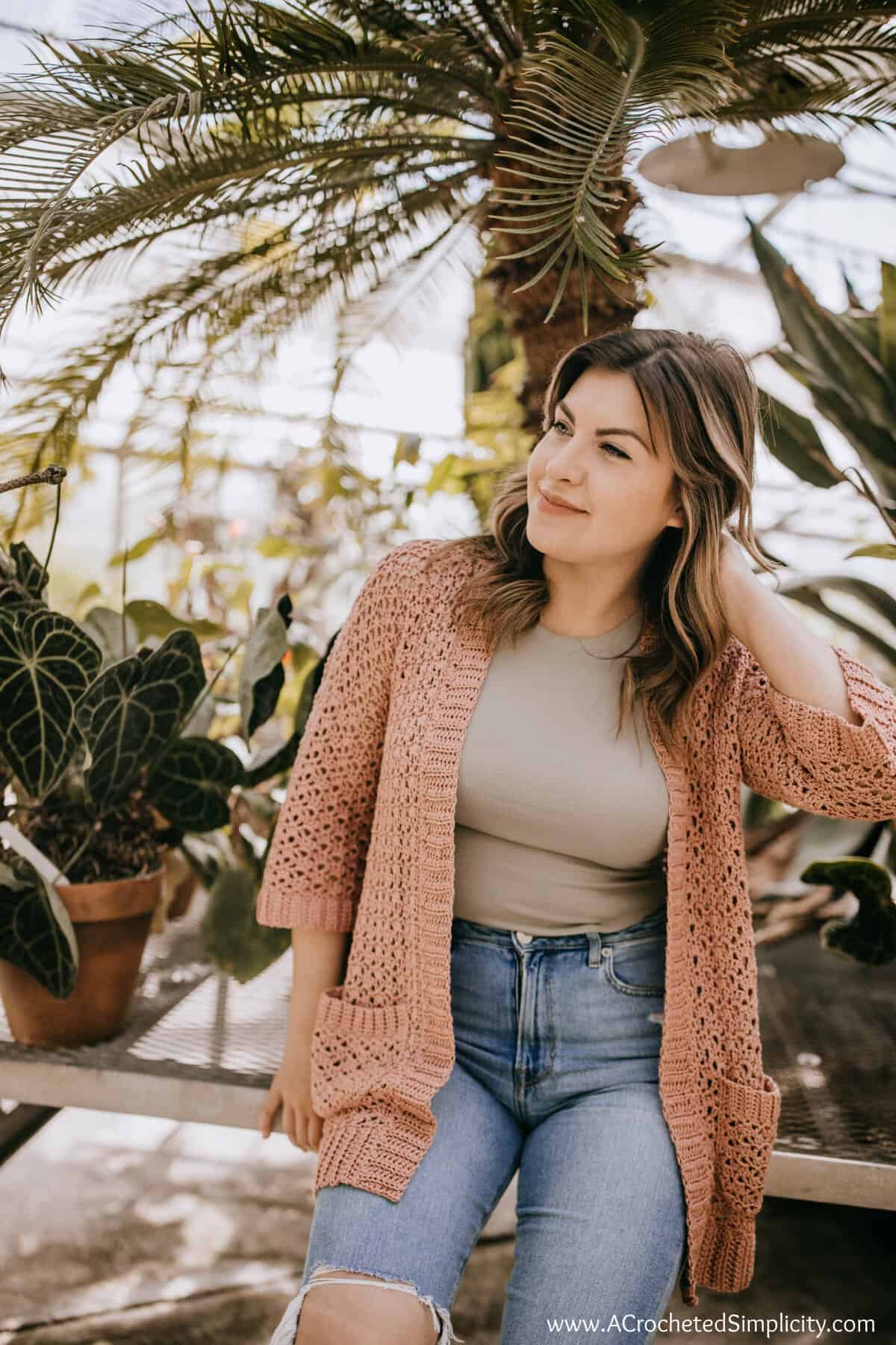 Woman wearing a mauve crochet summer cardigan with pockets.