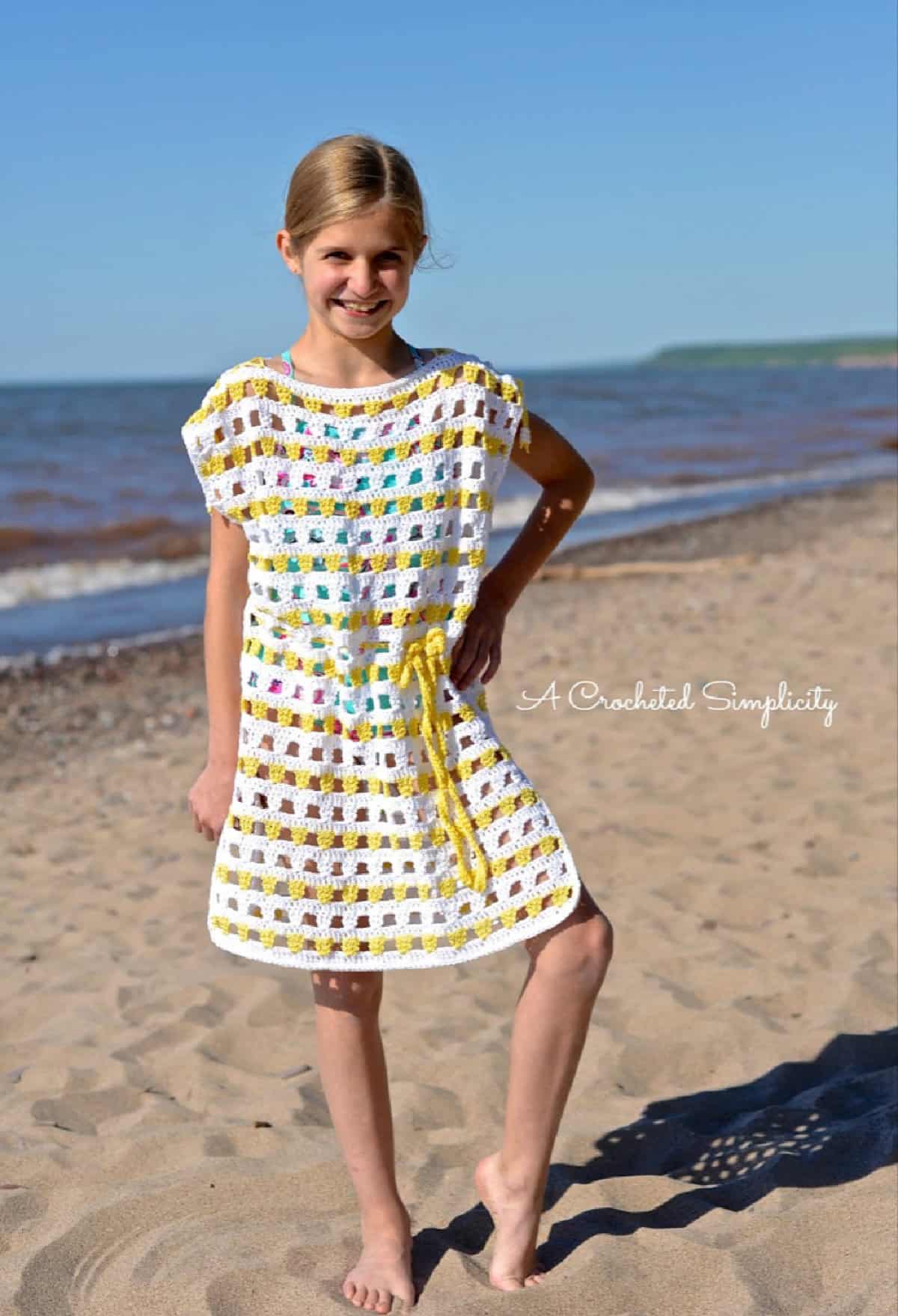 young girl modeling a white and yellow crochet beach cover up