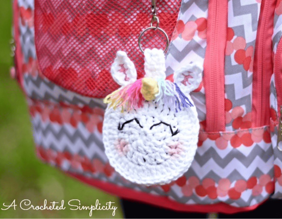 unicorn crochet earbud holder keyring hanging from a backpack