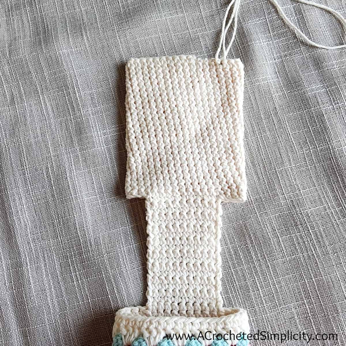 Cell phone pouch on a crochet chair caddy being sewn closed.