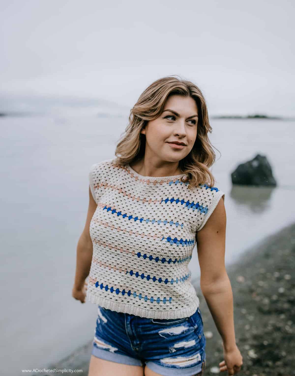 Woman on a beach modeling a vintage inspired crochet top pattern.