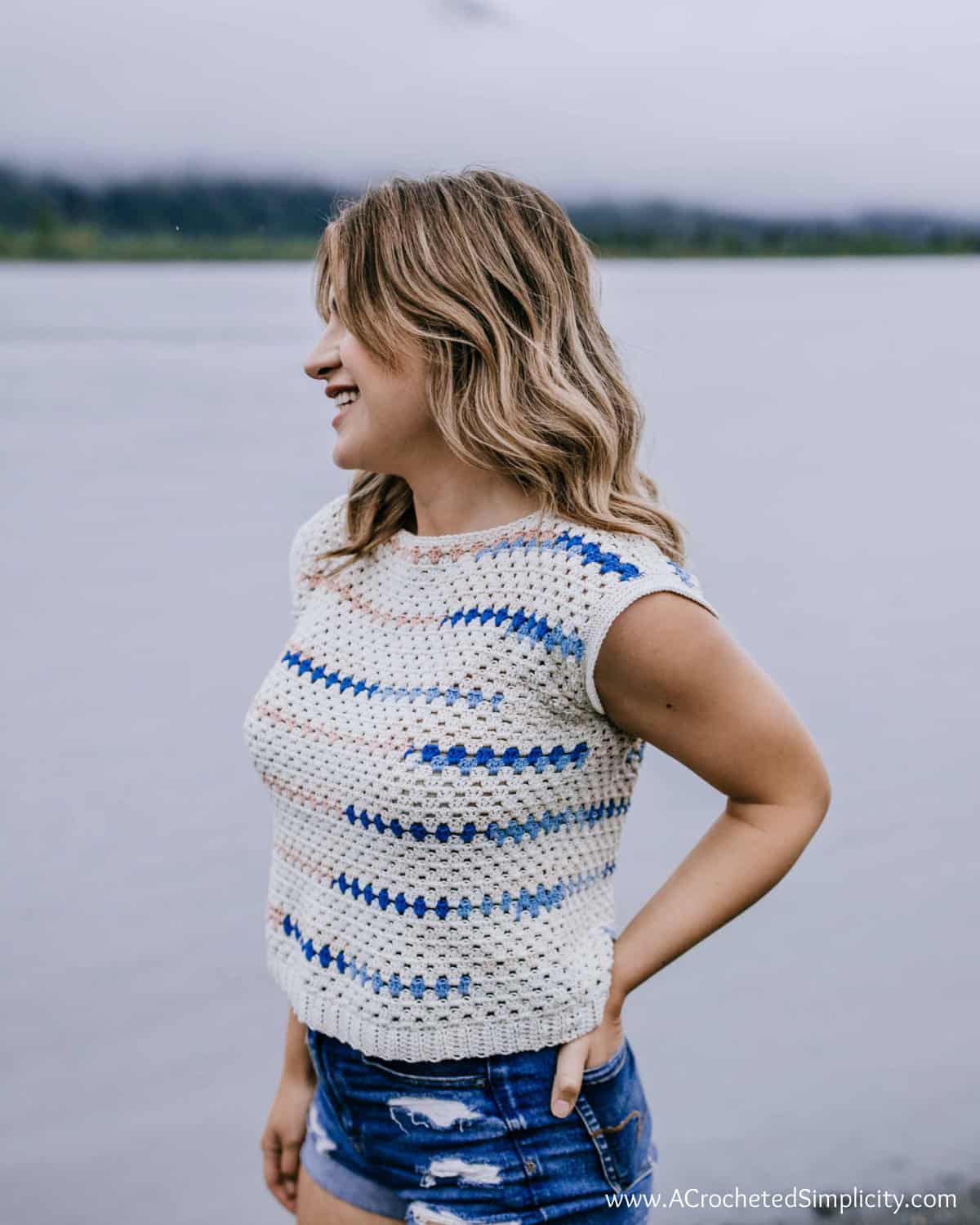 Model wearing a granny stitch crochet top in cream, pink and blue.