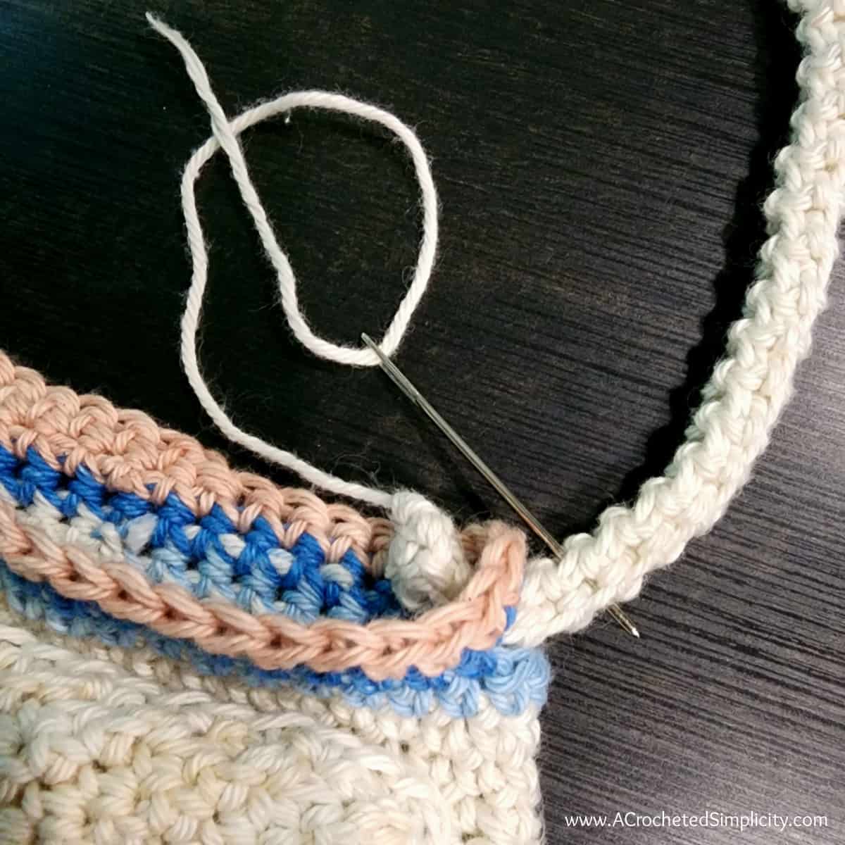 Adjustable crochet strap being secured to the top of the water bottle holder.