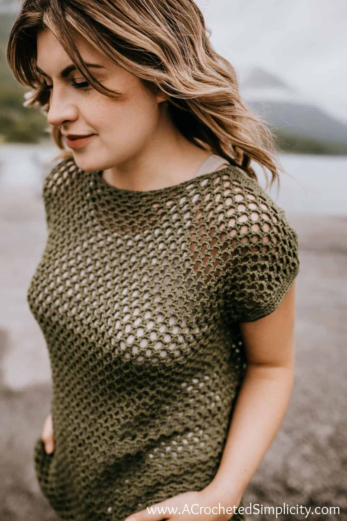 Model walking on the beach wearing a crochet mesh top pattern.