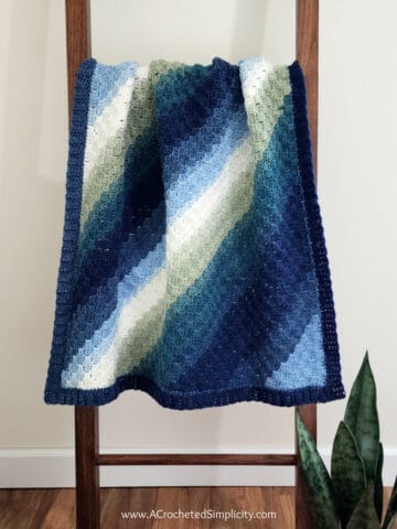 Diagonal box stitch C2C rectangle blanket hanging on a wooden blanket ladder.