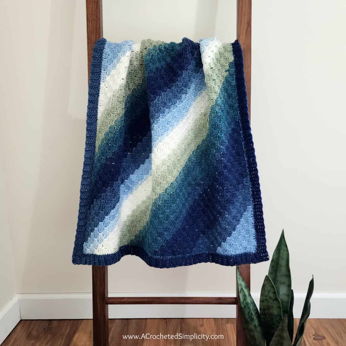 Diagonal box stitch C2C rectangle blanket hanging on a wooden blanket ladder.