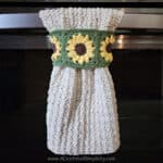 Sunflower crochet dish towel hanging on oven door handle.