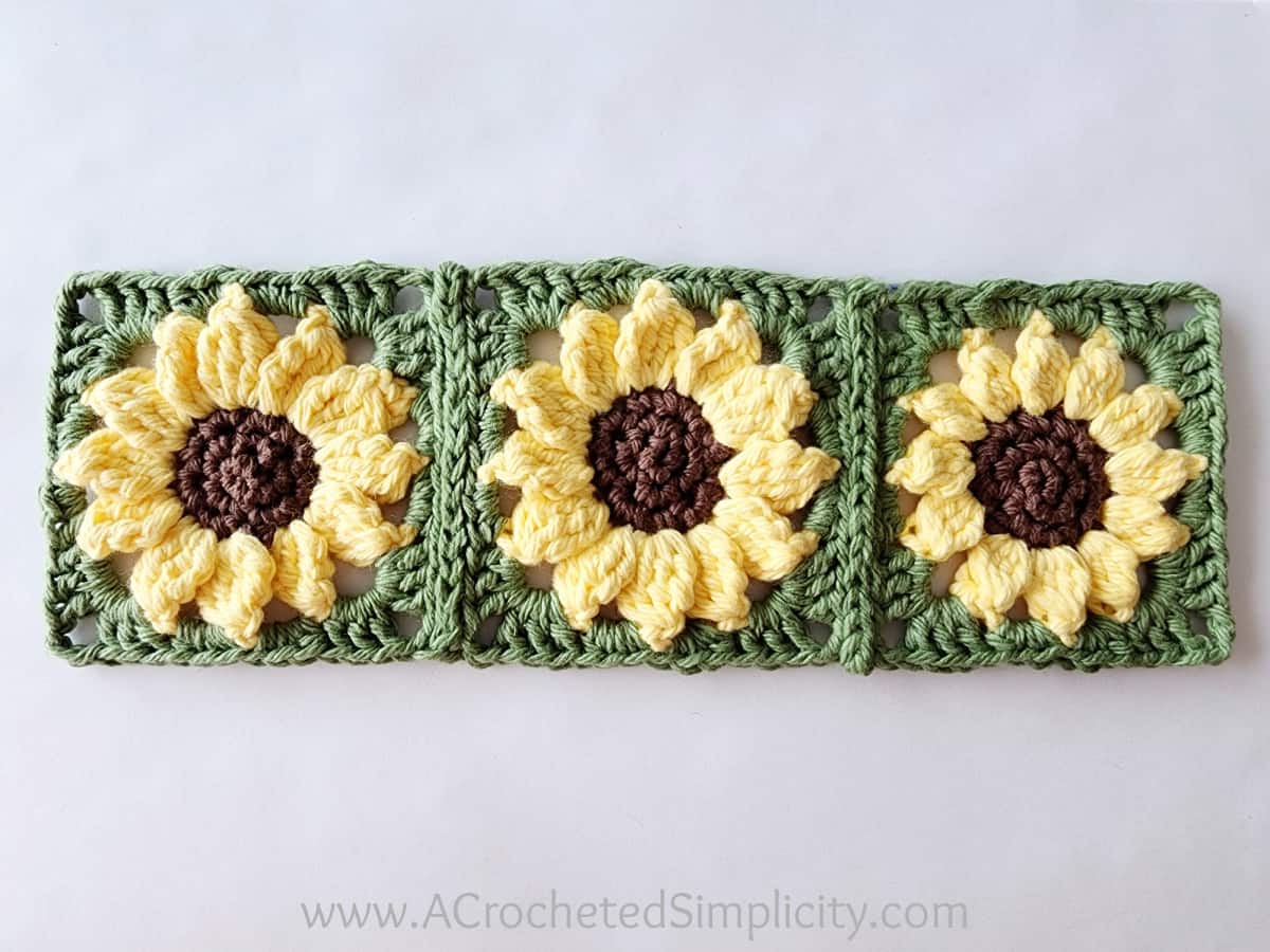 Three sunflower crochet motifs side by side and joined with slip stitch seams.